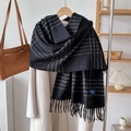 Close-up of black and white checkered scarf with long tassels on a beige coat - Black