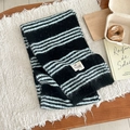 Detailed macro view of striped mohair blend knit scarf with brand bow label on textured rug - 135-175CM / Black