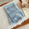 Detail eines weichen grau-blau gestreiften Strickschals aus Wolle mit Webetikett - Blaugrau