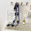 Sciarpa sottile in lana a righe blu e nere appesa a un gancio in legno in stile minimal - Righe blu e bianche