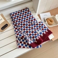 Detail of red and blue checkered knit wool scarf with a brand label on a cozy bench - Red and Blue Plaid