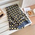 Detailed close-up of thick checkered knit scarf with wool texture and branded woven label - Yellow-Blue Plaid
