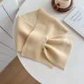 Creamy beige knit scarf with white flower pattern and label on a cozy winter table - Beige
