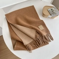 Bufanda de lana marrón con flecos y etiqueta sobre una mesa blanca elegante - Camel Oscuro