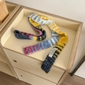 Bunter gestreifter Y2K Strickschal aus Bouclé-Garn auf einer beigen Holzoberfläche - Gelb Blau