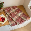 Soft checkered scarf in red and beige tones with fringe edges on a wooden surface - Dusky Pink