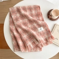 Détail d'une écharpe en maille à carreaux rose et blanc avec franges et texture douce - Rose