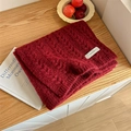 Thick burgundy knitted scarf with woven label on a light wood background - Wine Red