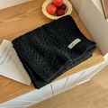 Chic black cable-knit scarf with minimalist woven tag on warm wooden surface - Black