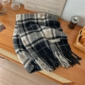 Plaid tassel scarf with boucle yarn and logo patch displayed on a wooden surface - Black Beige Grid