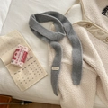Sciarpa in maglia grigio scuro con etichetta bianca su sfondo letto accogliente - 150x5cm / Grigio