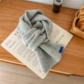Sciarpa grigia a maglia grossa con trama a coste ed etichetta blu su superficie in legno - Grigio chiaro / 60-80cm