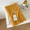 Ginger yellow wool scarf with fringes displayed on a white table in lifestyle setting - 175cm+ / Mango Yellow