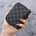 Compact black leather zipper wallet with geometric pattern shown in hand for size - Black