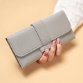Detailed macro view of the grey faux leather texture and decorative strap on woman's wallet - Gray