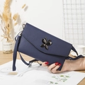 Navy blue crossbody phone bag with butterfly clasp and lychee texture on wooden table - Blue