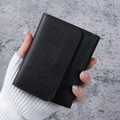 Minimalist black lychee pattern leather tri-fold wallet held in hand for daily use - Black