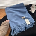 Elegant misty blue winter scarf with soft fringes styled on a dark coat background - Denim Blue