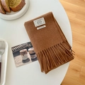 100% wool scarf in caramel brown with fringe details and woven label on table - Caramel color