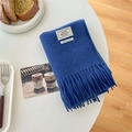 Dark blue 100% wool scarf with long tassels displayed on a minimal white table - Sapphire Blue