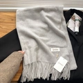 Soft light grey baby velvet scarf with tassels and brand tag on black coat - Moonlight Grey