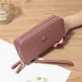 Long dusty pink wallet with double zippers and litchi grain texture in hand - Deep Pink