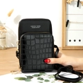 Chic black crossbody phone bag with faux crocodile texture and gold hardware on wood - Black