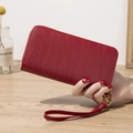 Cartera larga roja oscura con cremallera, textura ondulada y correa de muñeca - Granate