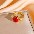 Detail of red round gemstone ring with clear zircon accents on a golden band - Gold Red Zirconia Ring