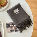 Dark grey 100% wool scarf with fringe detail shown on a minimalist white table - Dark Gray