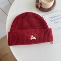 Dark red knit beanie featuring puppy embroidery and Lucky Pipiegg text on a white table - Hat—Wine Red