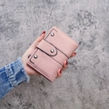 Pink matte leather trifold wallet with silver rivets held against a gray background - Pink