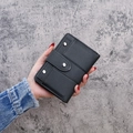 Short vintage frosted black leather trifold wallet with silver rivets held by hand - Black