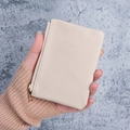 Elegant cream pebbled leather mini wallet with gold zipper held in hand for size - Off-white