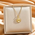 Goldene Kleeblatt-Halskette aus Titanstahl auf luxuriösem Seidenhintergrund präsentiert - Antikes Gold Vierblättriges Kleeblatt