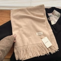 Elegant beige cashmere-feel tassel scarf displayed on a black coat in a lifestyle setting - Oatmeal Beige