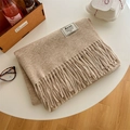 Beige faux cashmere scarf with tassels and brand label on a cozy wooden desk - Oatmeal