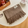 Thick coffee brown knit scarf with tassels and brand label on a cozy gift table - Dark Chestnut