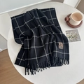 Thick black and white plaid scarf with tassels and vintage label on a white table - Large Plaid Black