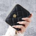 Women's black quilted wristlet wallet featuring a golden camellia flower and metal zipper - Black