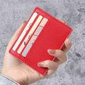 Slim red faux leather card holder with three slots shown in a hand-held display - Red