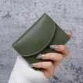 Minimalist olive green PU leather short wallet with curved flap held in hand - Dark Green