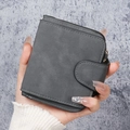 Petit portefeuille femme en cuir mat gris foncé avec fermoir à pression tenu à la main - gris foncé