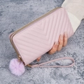 Pink V-quilted long wallet with double zippers and soft pompom charm held by a hand - Purple