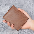 Klassische braune Herren-Brieftasche mit Lychee-Ledertextur in der Hand gehalten - Braun