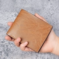Kurze Herren-Bifold-Geldbörse aus braunem Leder mit Litschi-Struktur in der Hand - Khaki