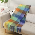 Bufanda de cuadros de colores en mohair con flecos sobre un sofá en ambiente hogareño - Cuadros Azul Multicolor