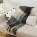 Primer plano de bufanda gruesa de mohair a cuadros con flecos en un sofá beige - Cuadros Coloridos Negro