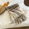 Bufanda de cuadros de mohair con flecos en crema y gris sobre una cama acogedora - Beige