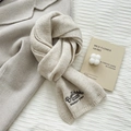 Beige knit wool scarf with elegant embroidery paired with warm winter coat and candle - Off-white